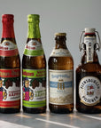 Six different beer bottles arranged in a row against a neutral background. The bottles include various beer styles such as Tegernseer Helles, Flensburger Pils, Bayreuther Hell, Rothaus Tannenzäpfle, Rothaus Schwarzwald Maidle Naturtrüb, Rothaus Radlerzäpfle Limette.
