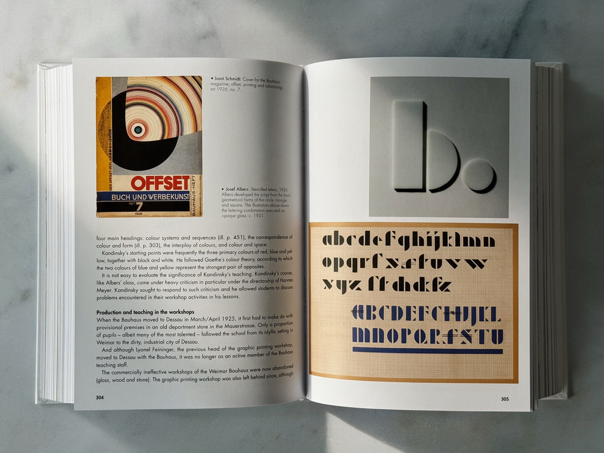 An open Bauhaus book spread displayed on a light grey marble surface, showing printed typography and a colour sample panel.
