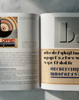 An open Bauhaus book spread displayed on a light grey marble surface, showing printed typography and a colour sample panel.